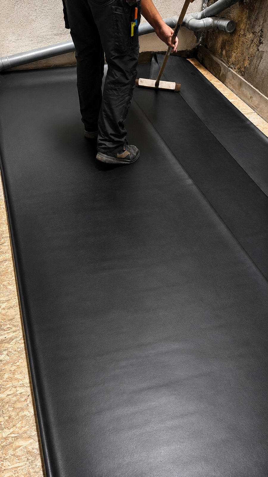 Marouflage d'une membrane EPDM au balai lors de la pose à froid sur un toit plat, par A2Roulet-Toiture