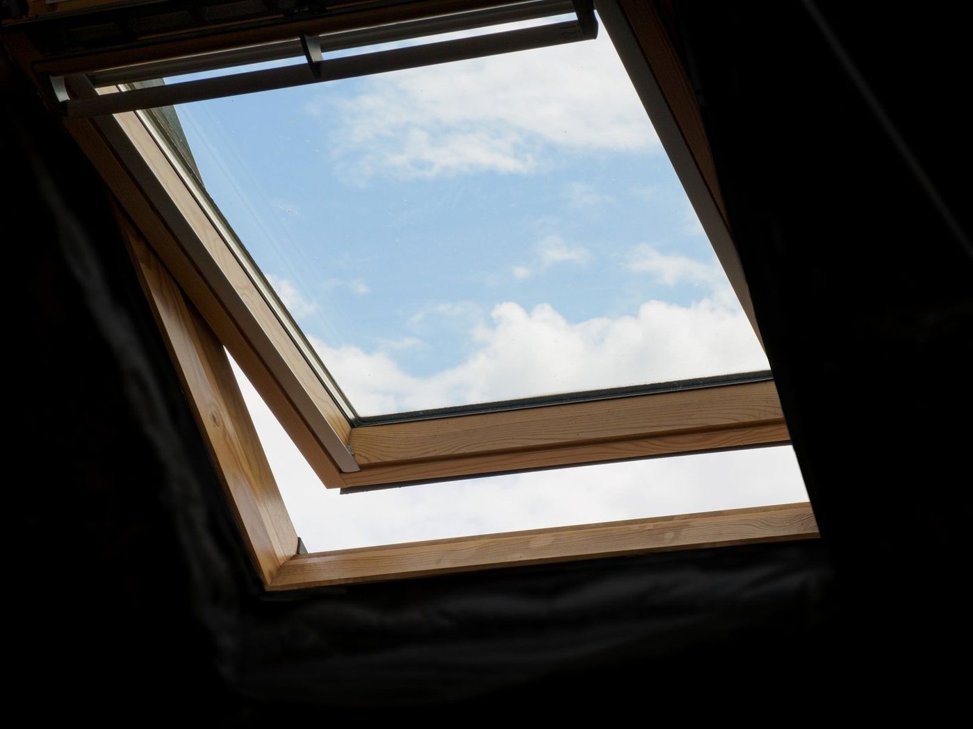 Fenêtre de toit Velux ouverte sur un ciel bleu, posée par A2Roulet-Toiture en Gironde