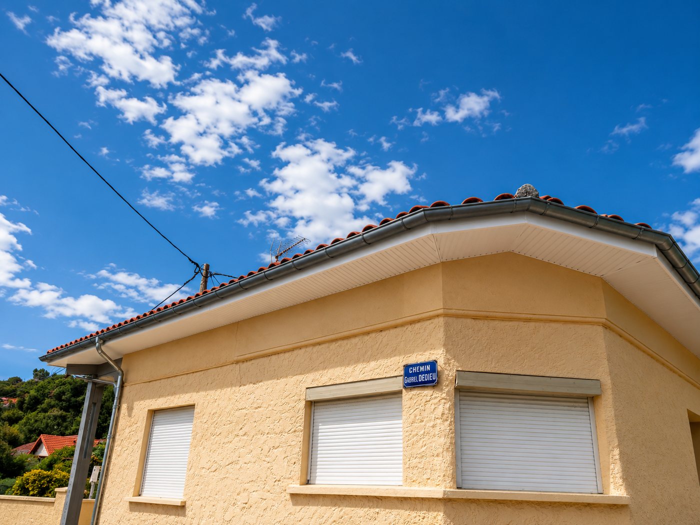 Habillage d'avant-toit en aluminium anthracite avec gouttière assortie sur une construction en brique, réalisé par A2Roulet-Toiture
